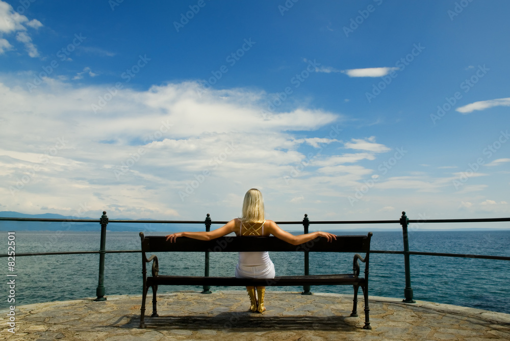 Woman sitting on a bench and looking at sea