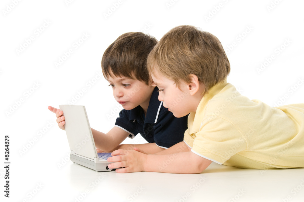 Two children playing with the laptop lying on the floor Two children playing with the laptop lying on the floor