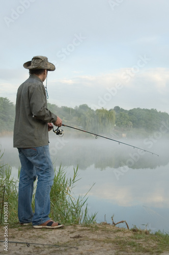 fisherman on a morning foggy lake