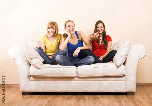 three girls sitting on a lounge are laughing