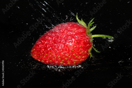 Strawberry and sparks of water on a dark background.
