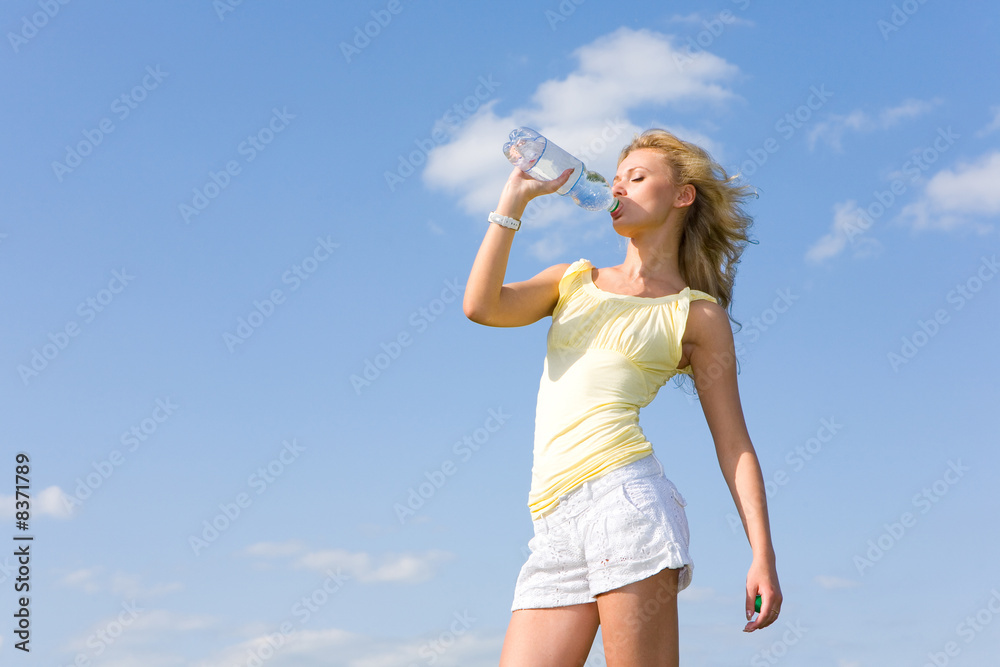 Beautiful girl drinking water against blue sky Beautiful girl drinking water against blue sky