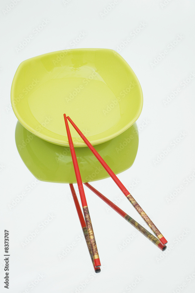 Red plate and chopsticks on reflective background Red plate and chopsticks on reflective background