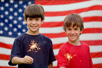 Boys at Twilight Holding Sparklers in Front of Flag
