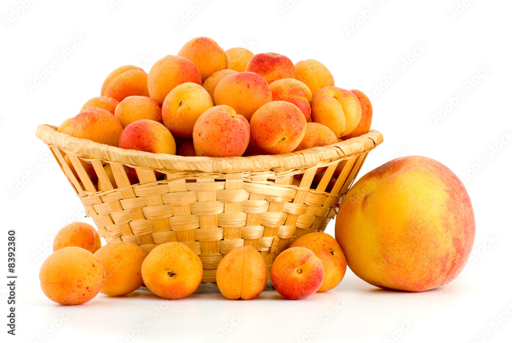 Wicker basket filled with apricots and single peach near Wicker basket filled with apricots and single peach near