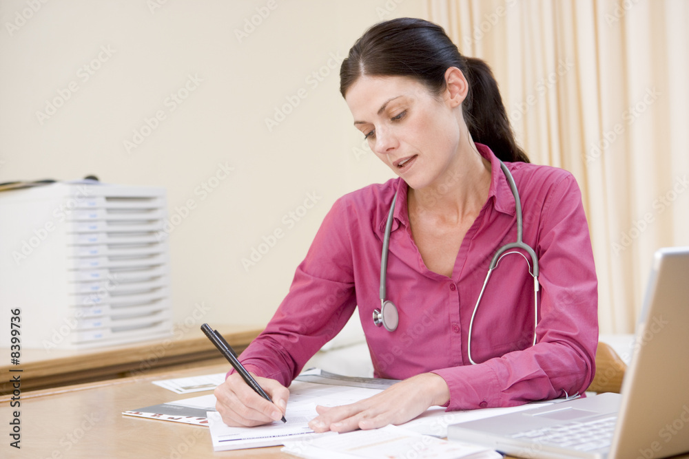 Doctor with laptop writing in doctor's office Doctor with laptop writing in doctor's office