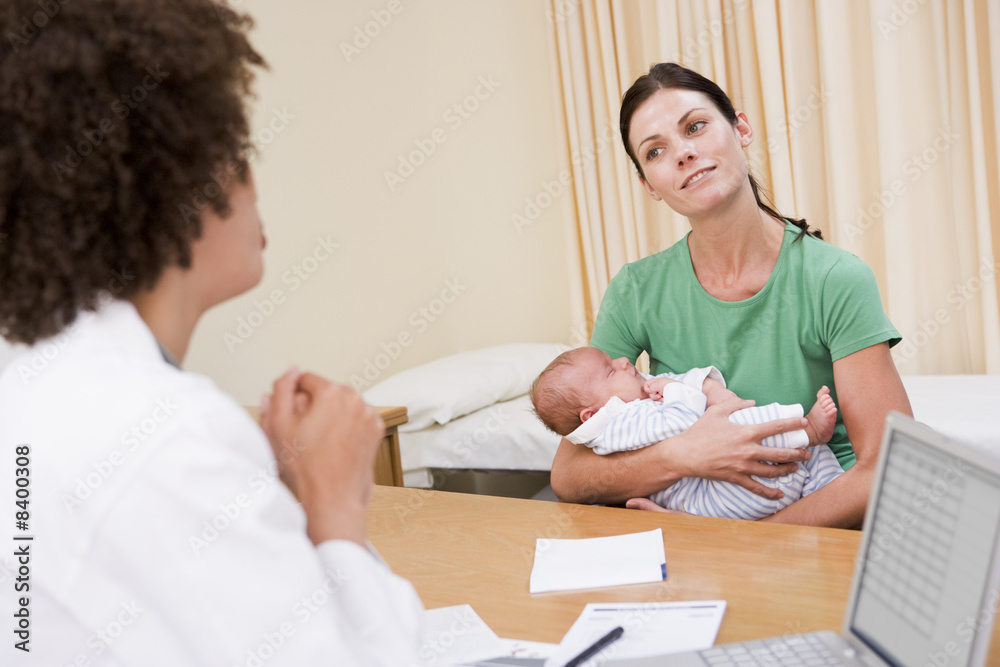 Doctor with laptop and woman in doctor's office holding baby Doctor with laptop and woman in doctor's office holding baby