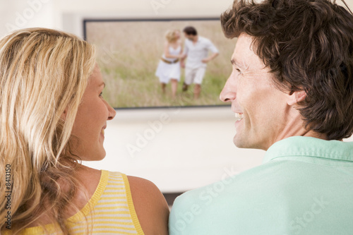 Couple in living room watching television smiling