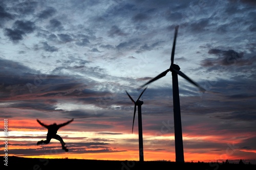 wind farm at dusk with a jumping man - a silhouette