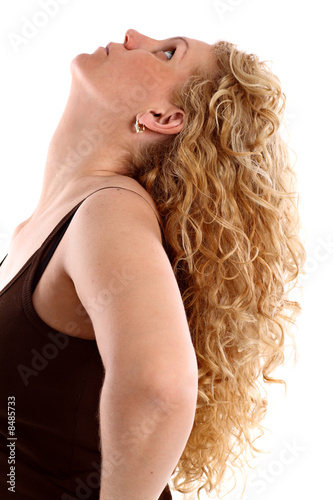 Young woman with long blonde curly hair looking up, on white.