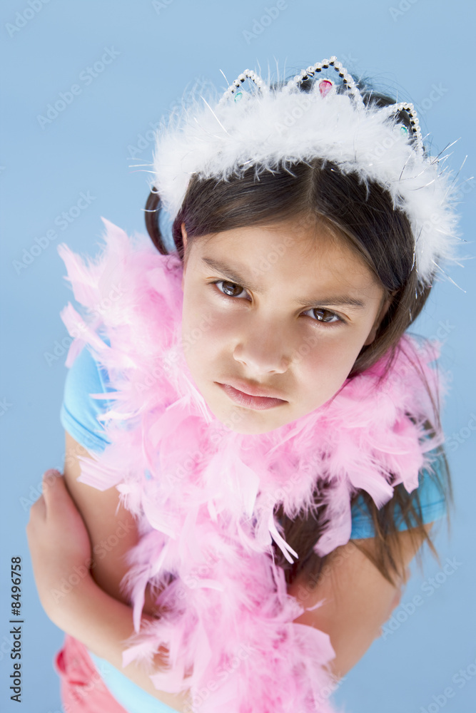 Young girl wearing crown and feather boa frowning