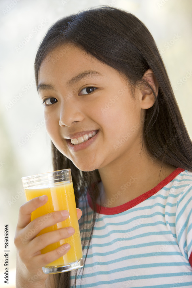 Young girl indoors drinking orange juice smiling Young girl indoors drinking orange juice smiling