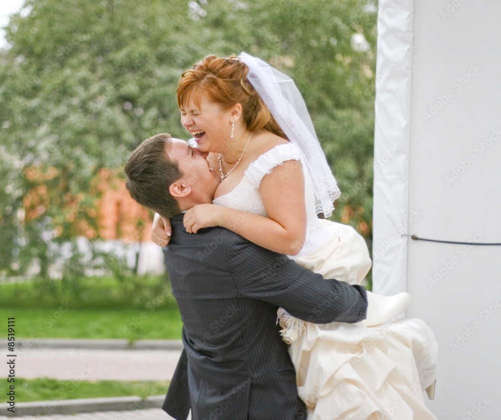 Fototapeta premium groom embracing laughing plump bride in the park