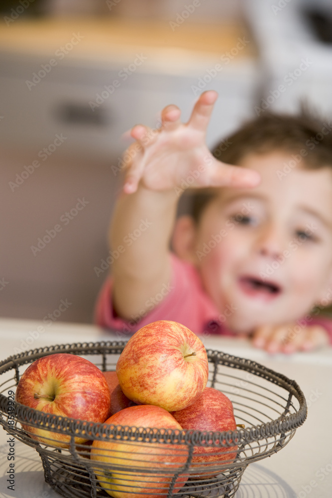 Fototapeta premium Young boy getting apple off counter