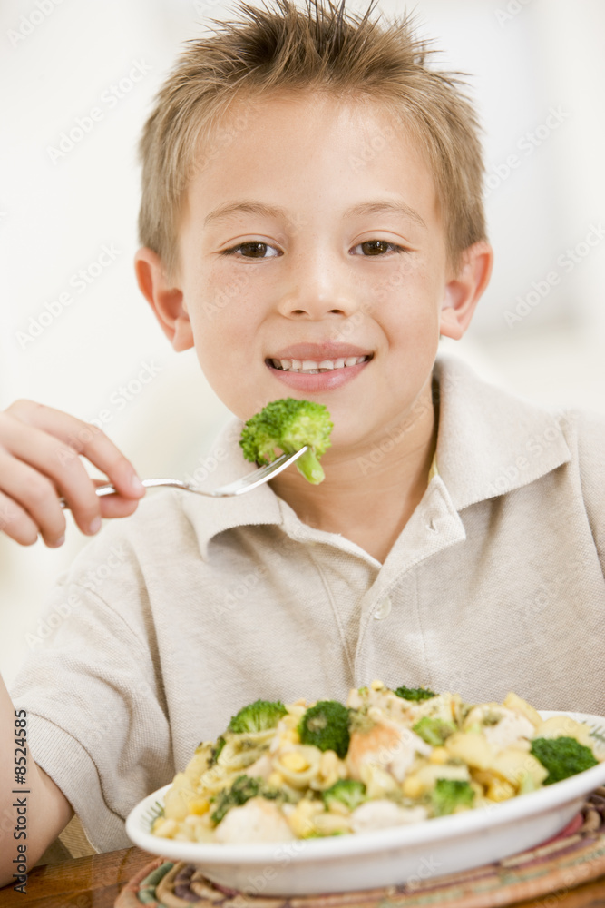 Young boy eating pasta with brocolli smiling Young boy eating pasta with brocolli smiling