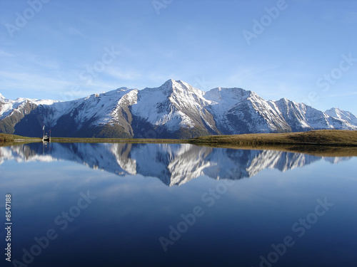 Reflection in the water of the quiet Bettmersee Lake in Valais