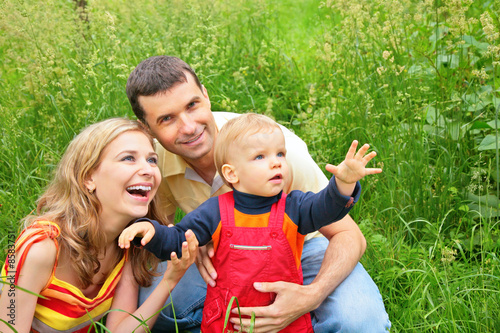 Φωτογραφία Parents with child sit in grass and look upwards