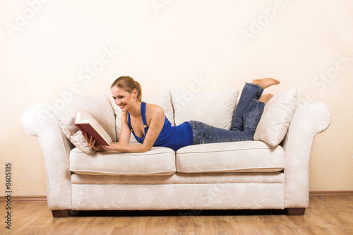 young woman is reading a book on a lounge