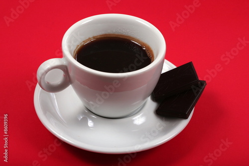 white coffee cup on red background with chocolate