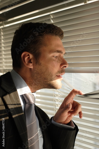 curious man looking through wingow blinds photo