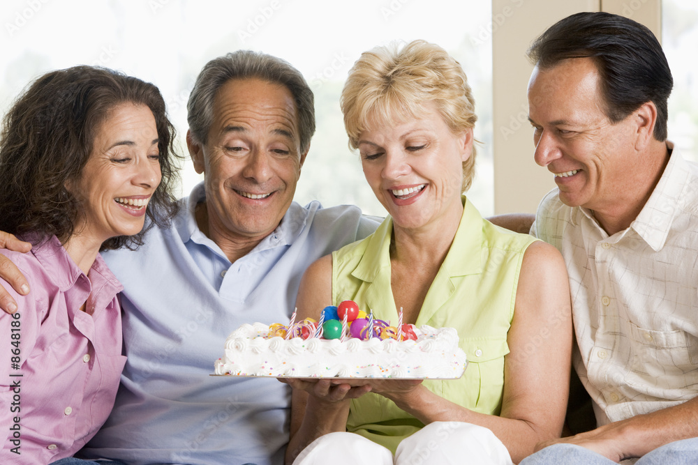 Two couples in living room with cake smiling Two couples in living room with cake smiling