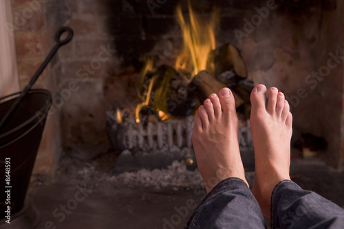 Feet warming at a fireplace