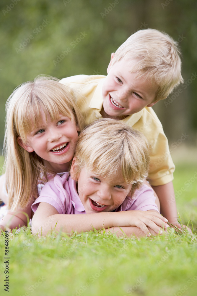 Three young children playing outdoors smiling Three young children playing outdoors smiling