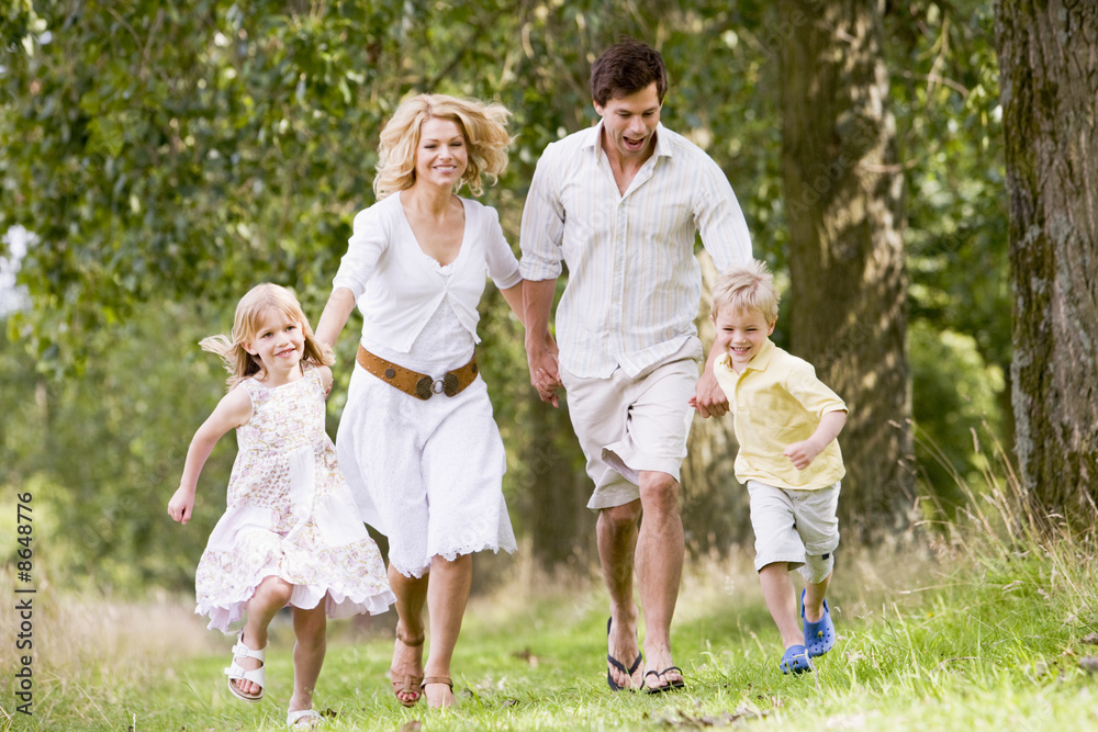 Family running on path holding hands smiling