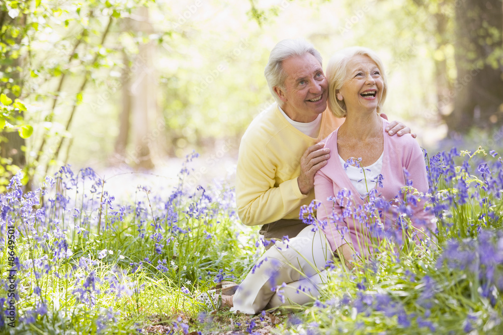 Couple sitting outdoors with flowers smiling Couple sitting outdoors with flowers smiling