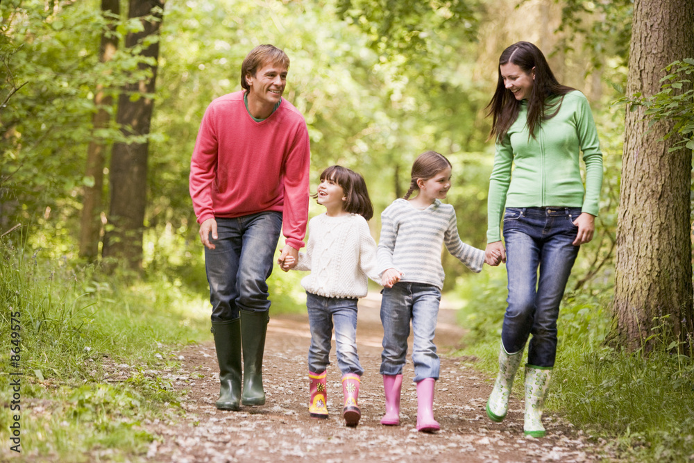 Fototapeta premium Family walking on path holding hands smiling