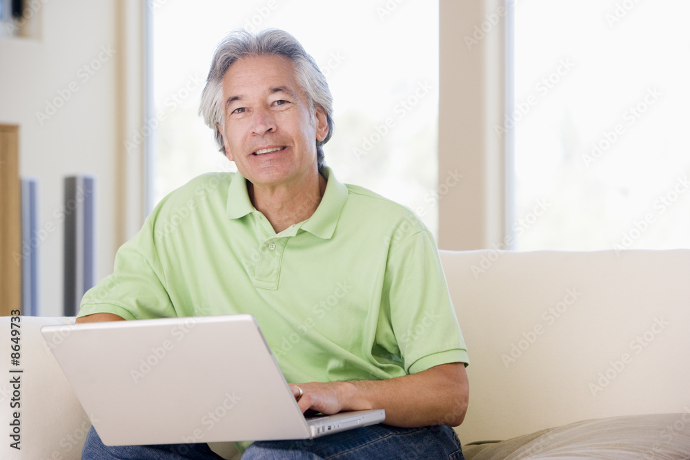 Man in living room with laptop smiling Man in living room with laptop smiling