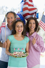 Family outdoors on fourth of July with flags and cookies smiling