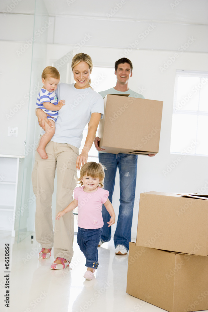 Family with box moving into new home smiling Family with box moving into new home smiling