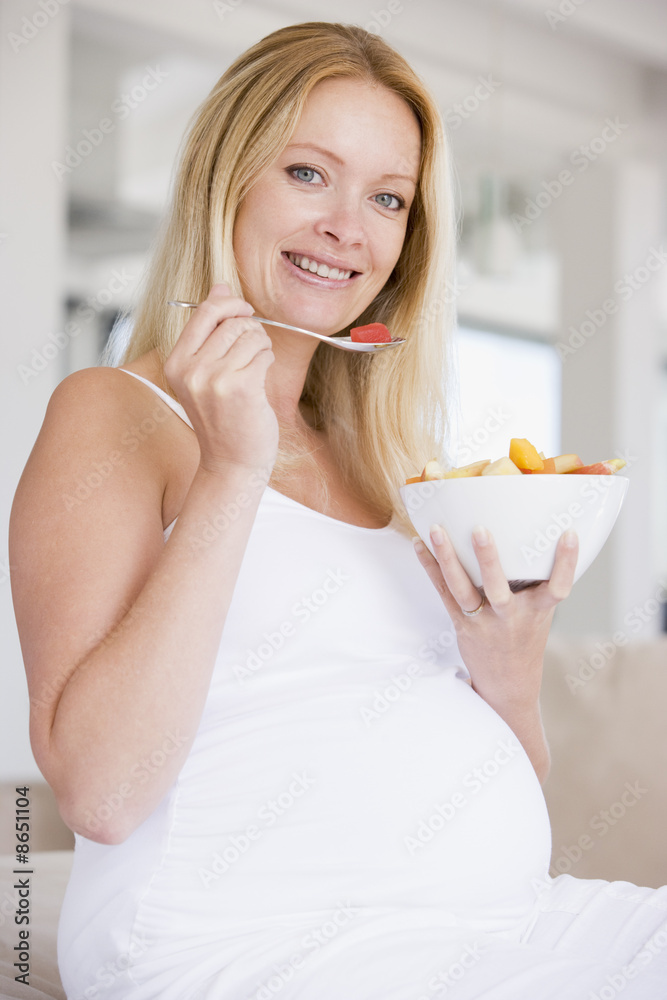 Pregnant woman with bowl of fruit salad smiling Pregnant woman with bowl of fruit salad smiling