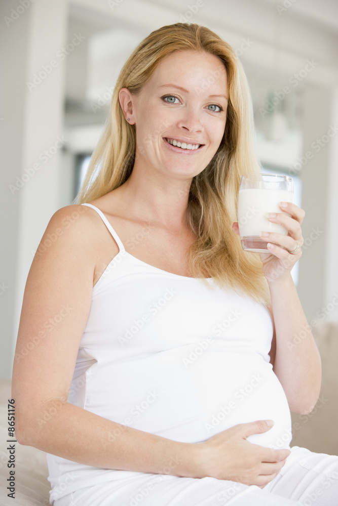 Pregnant woman with glass of milk smiling