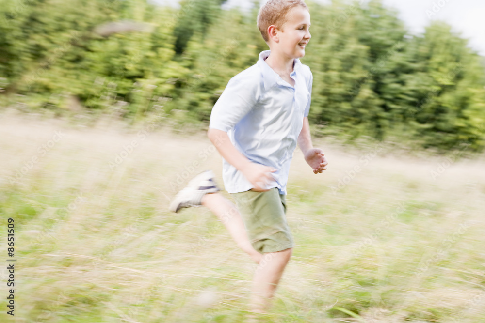 Young boy running in a field smiling Young boy running in a field smiling