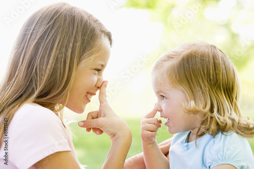 фотографія Two sisters playing outdoors and smiling