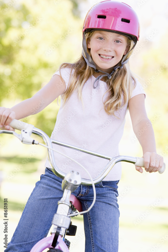 Young girl on bicycle outdoors smiling