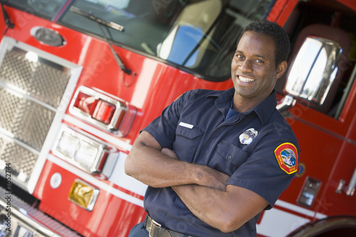 Slika na platnu Portrait of a firefighter by a fire engine
