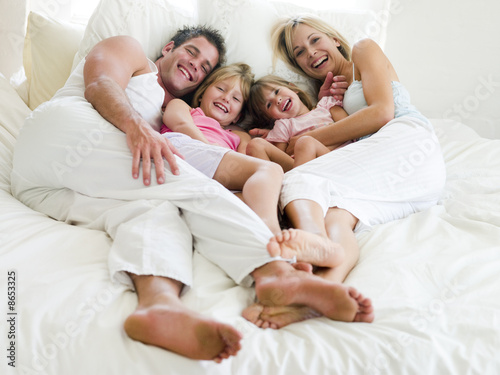Family lying in bed smiling