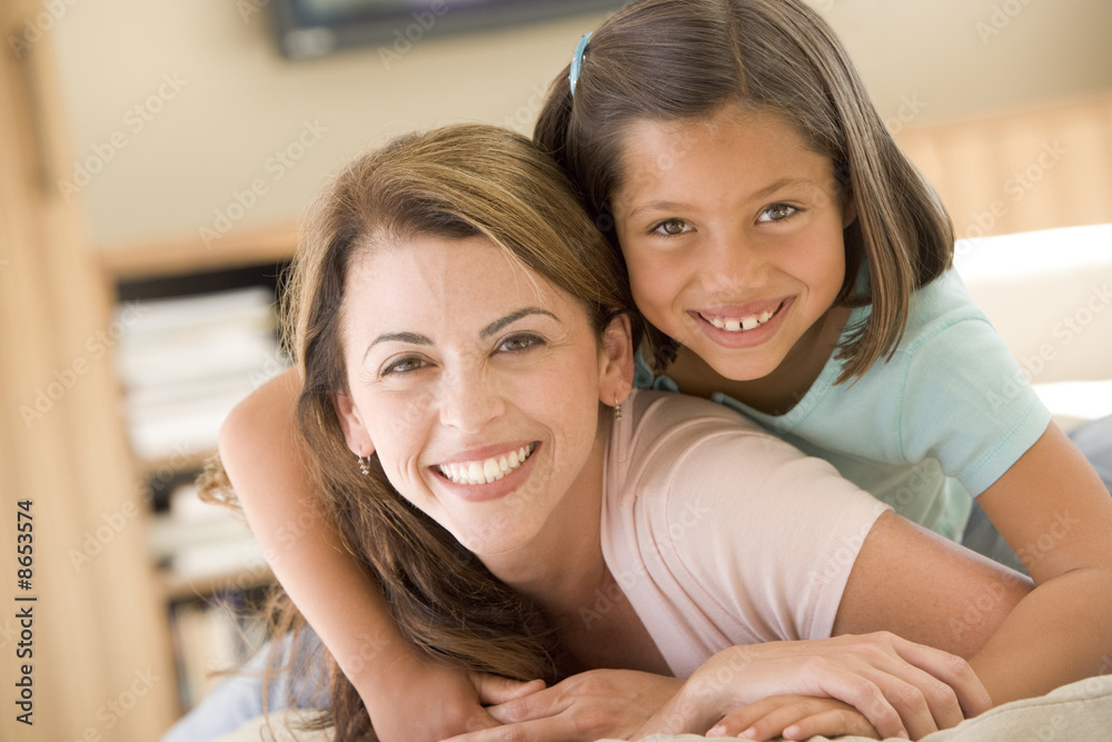 Woman and young girl in living room smiling Woman and young girl in living room smiling