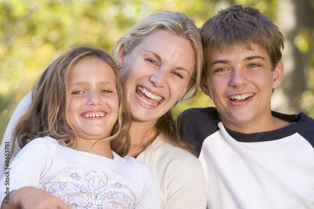 Woman and two young children outdoors laughing Woman and two young children outdoors laughing