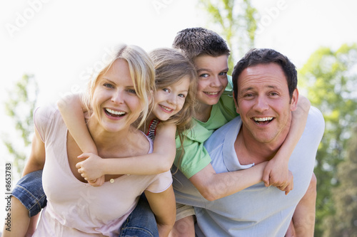 Couple giving two young children piggyback rides smiling Fototapet