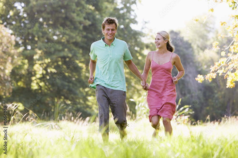 Fototapeta premium Couple running outdoors holding hands and smiling