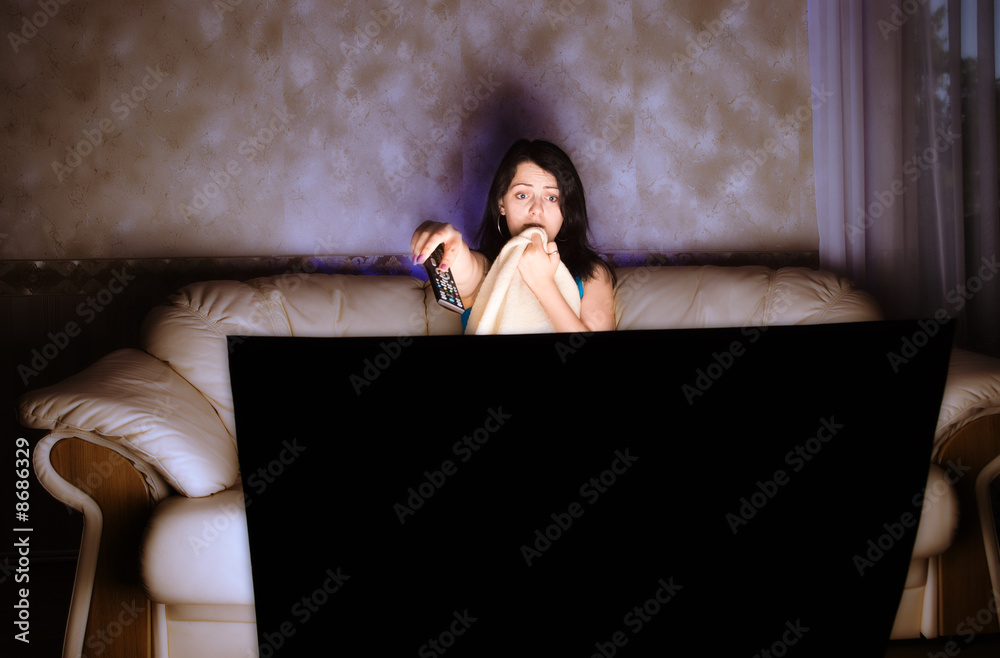 Fototapeta premium scarried beautiful girl watching TV on a couch