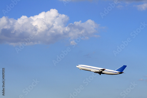 Modern passenger plane flying in blue sky with clouds