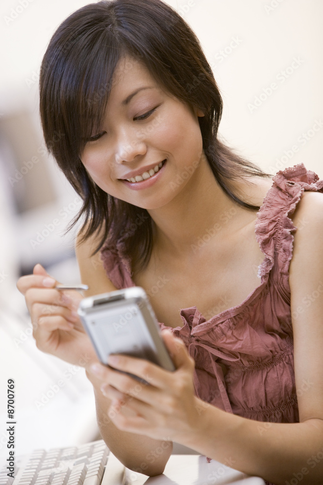 Woman in computer room using personal digital assistant smiling Woman in computer room using personal digital assistant smiling