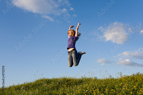 Jumping girl on the green meadow