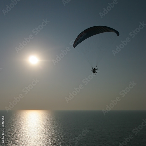 paraglider on sunset flying over the sea