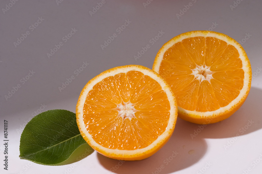 Fototapeta premium Two orange slices with leaf on white background with shadow